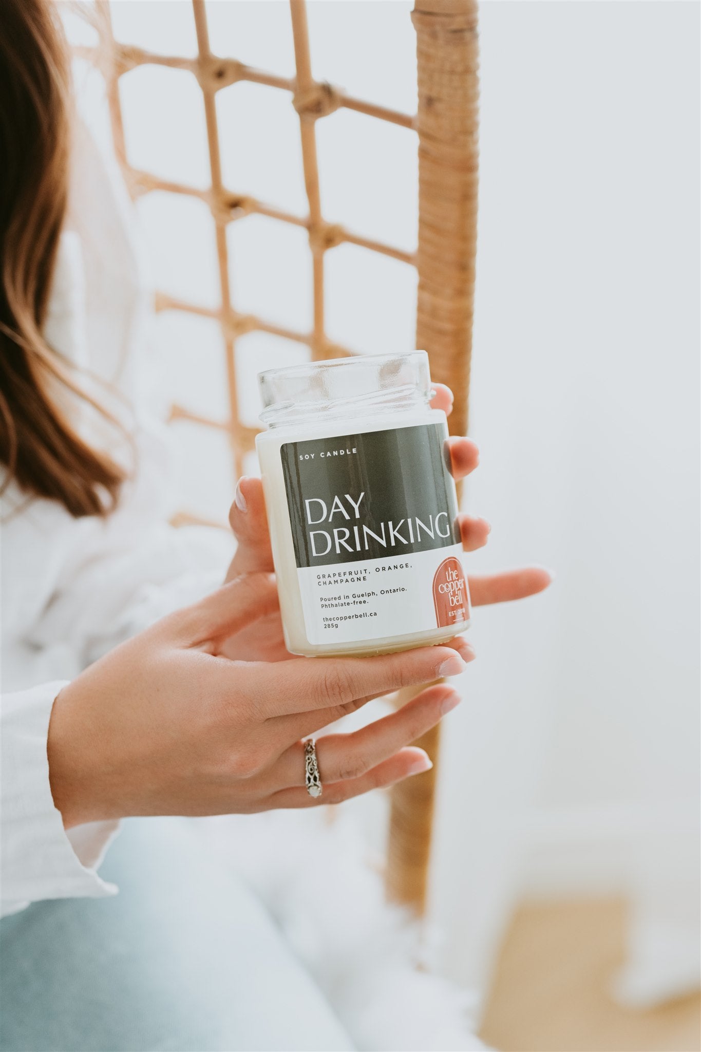 guelph candle store. photo of day drinking soy candle, held by model to display label.