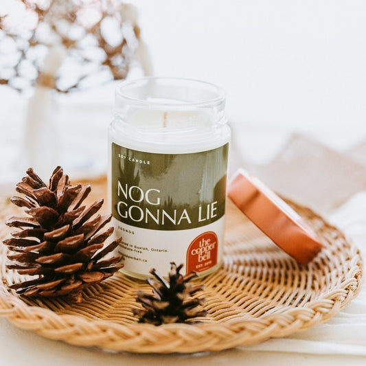 nog gonna lie. eggnog scented candle with christmas home decor. dried pinecones surround the scented candle.