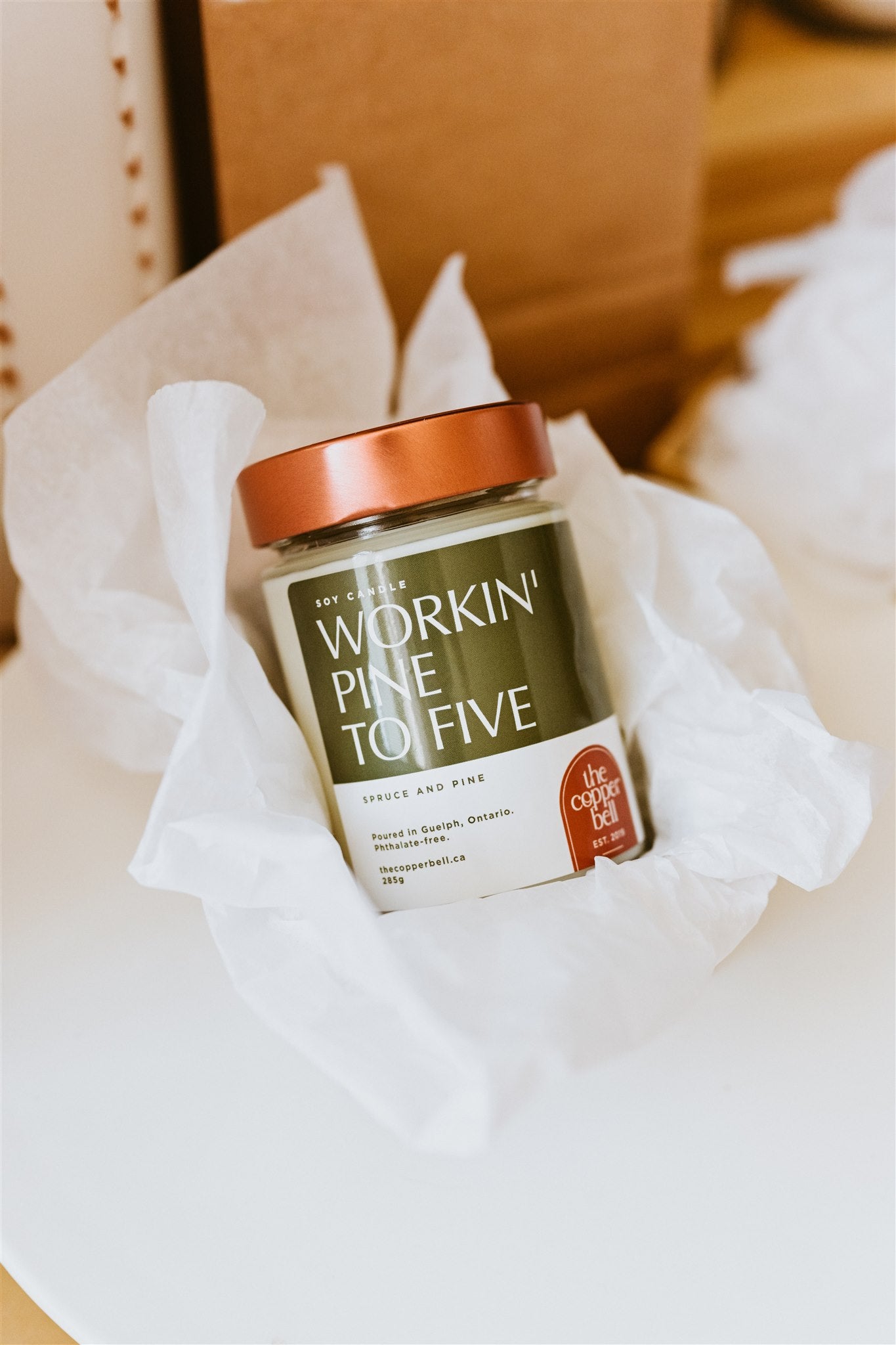 Christmas tree scented candle called workin' pine to five. Displayed in a gift box with white tissue paper. Perfect Christmas candle gift