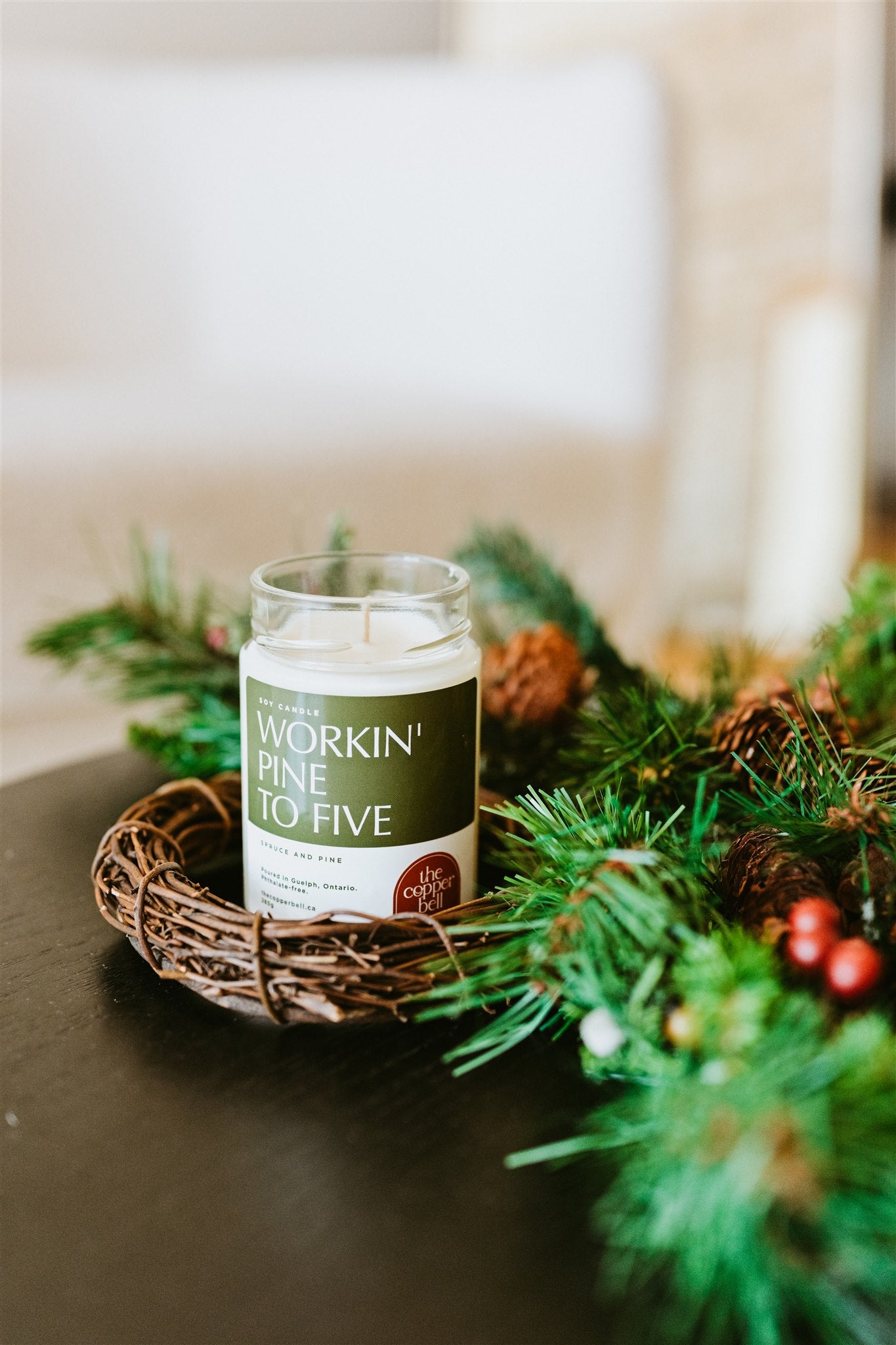 christmas tree scented candle named workin' pine to five. displayed on a table with christmas decor.