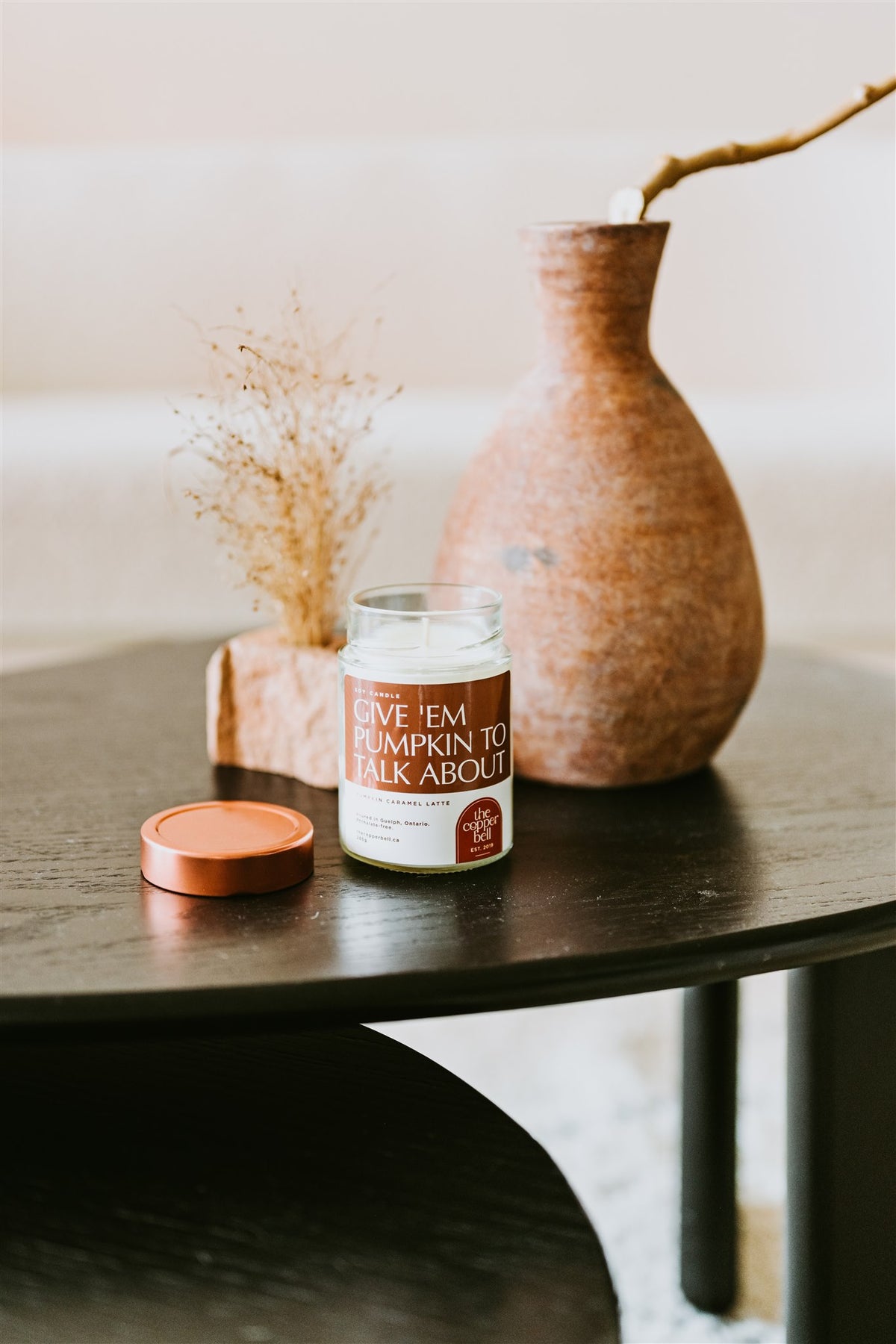 funny soy candle displayed on a dark wooden coffee table. give 'em pumpkin to talk about candle