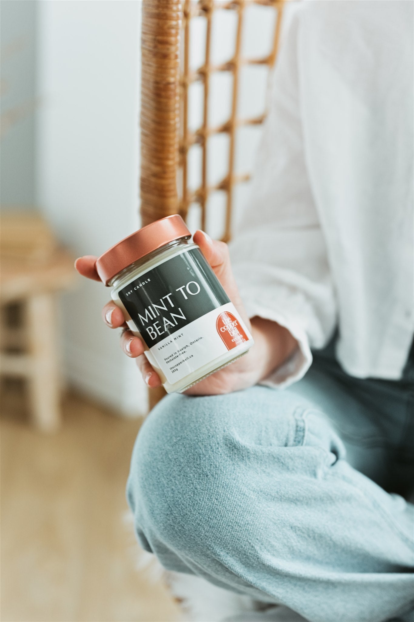vanilla mint scented candle held by woman wearing white shirt and blue jeans.