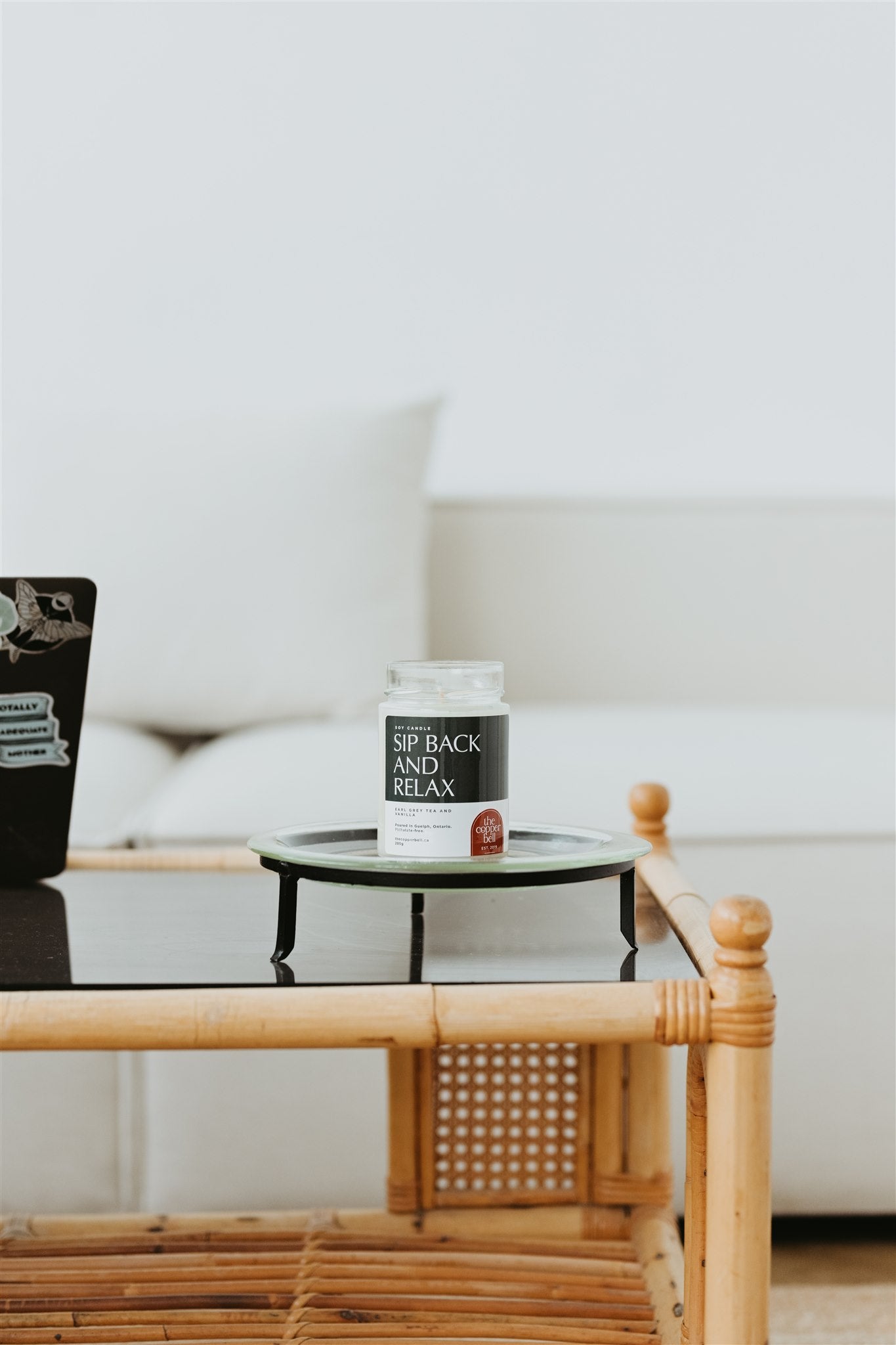 sip back and relax candle displayed on a wicker coffee table.