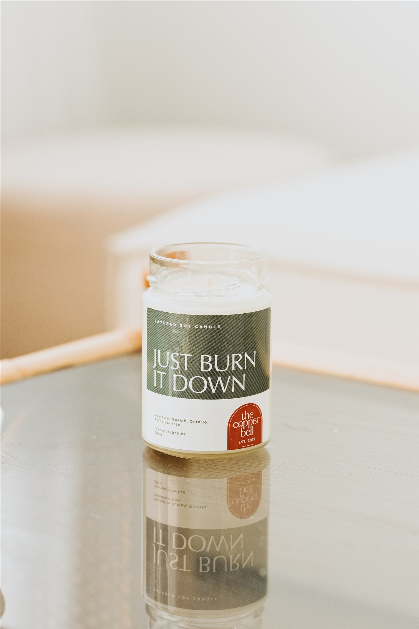 just burn it down soy candle. layered candle displayed on a glass table top, the label reads just burn it down